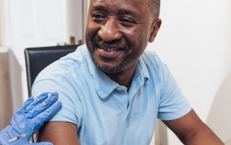 A person sitting down receiving a vaccination by a health professional