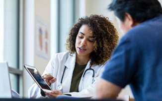 A health professional accessing a patient's record on a tablet device and discussing it with another health professional
